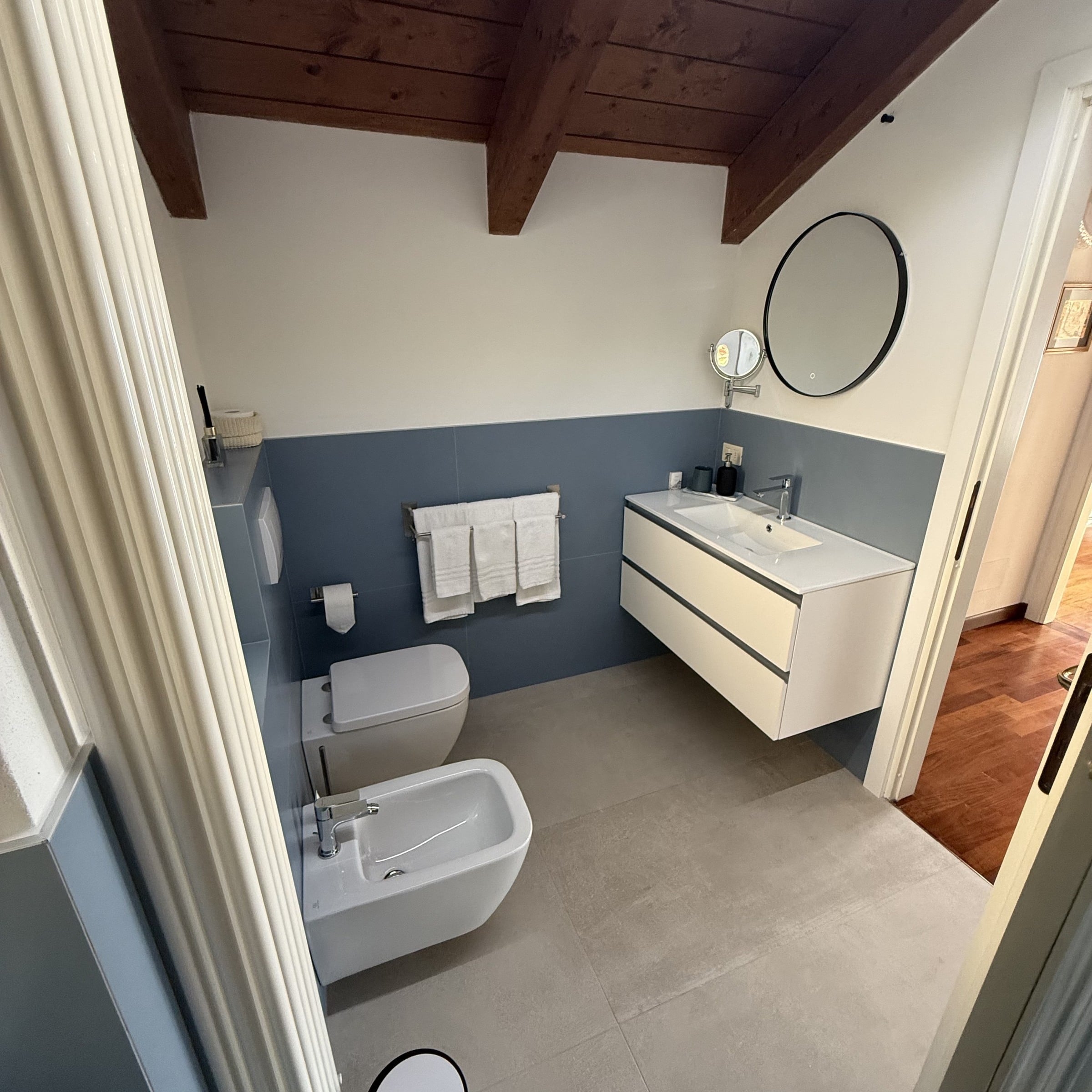 First bathroom with natural light, wall-mounted toilet and bidet beneath exposed timber beams