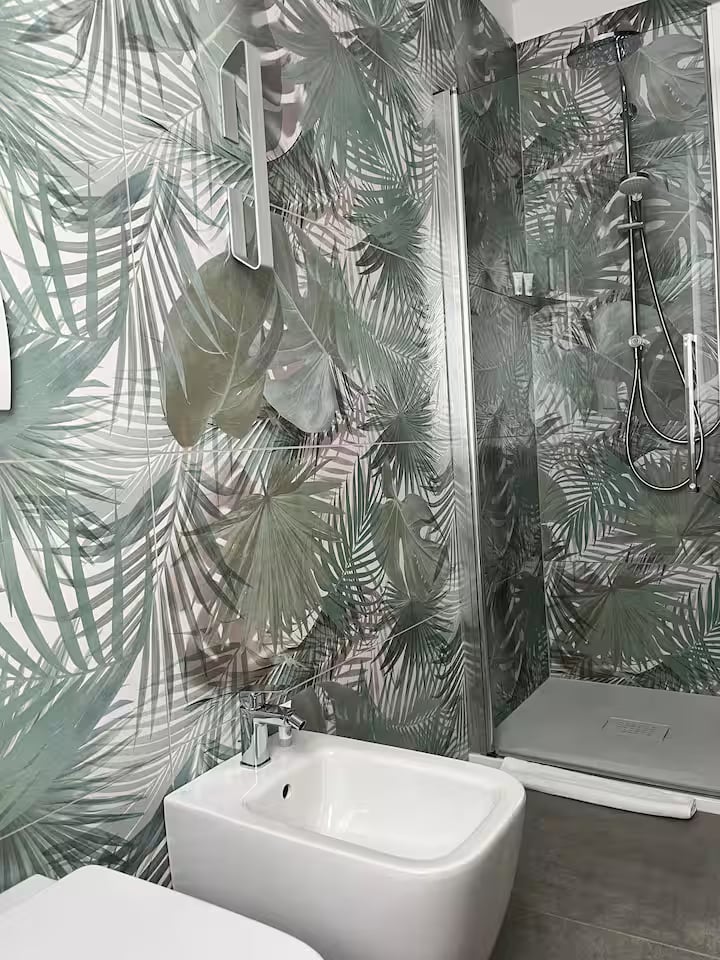 Glass-enclosed shower and bidet in the second bathroom with botanical wall finishes