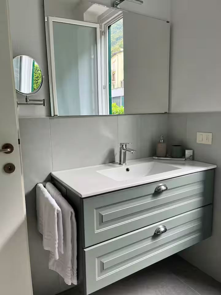 Second bathroom vanity with a wide basin, large mirror and natural light from the window