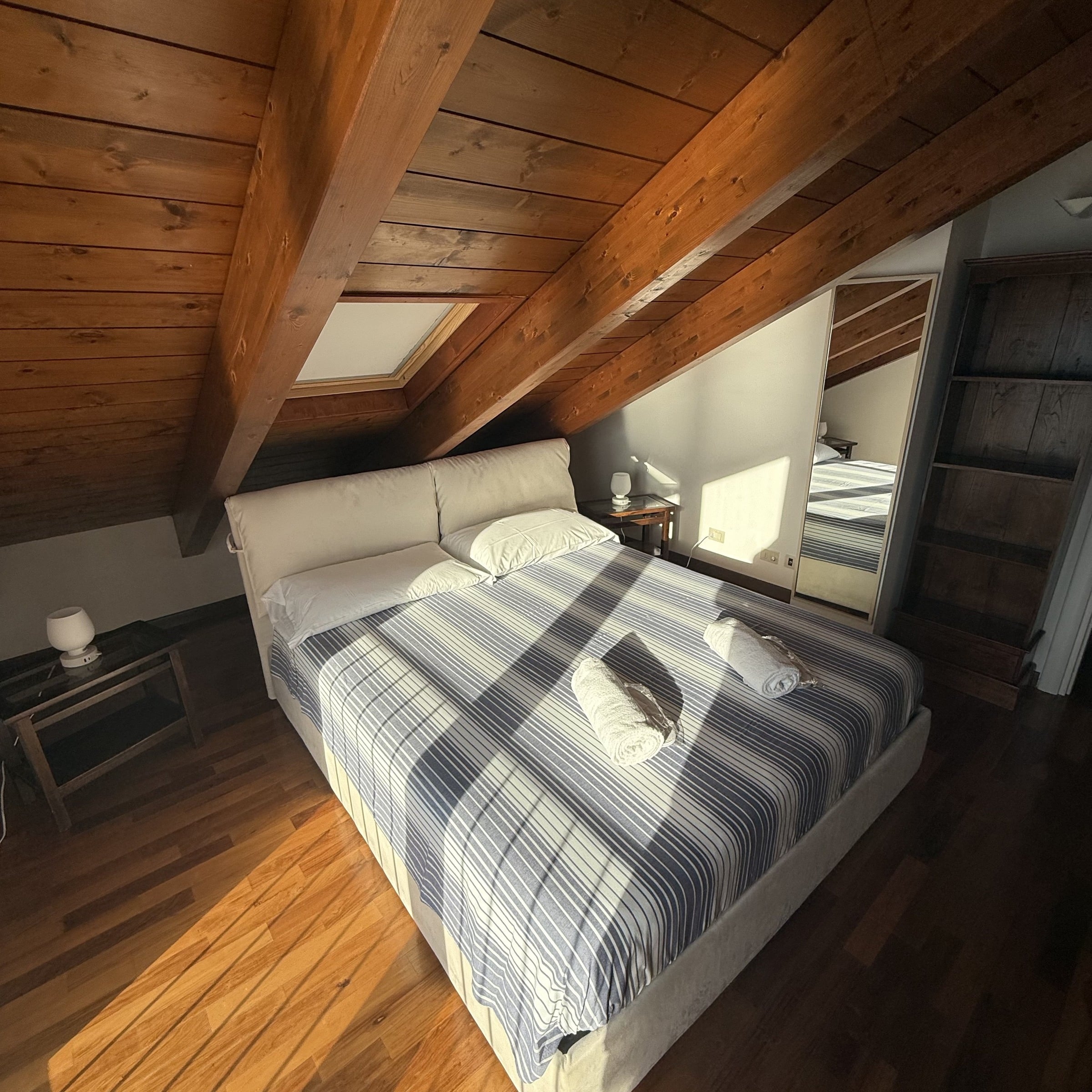 Double bedroom beneath exposed timber beams, prepared with fresh linen and towels